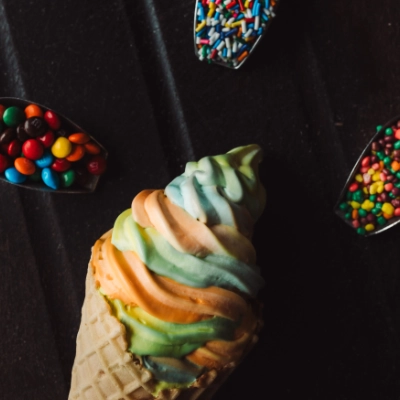 Cornet de molle multisaveurs aux couleurs de l'arc-en-ciel, entouré de bonbons